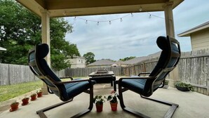 A covered patio with two reclining chairs, a small table, and string lights. - Comfy & spacious home (Austin)