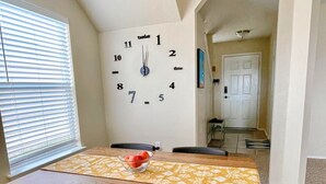 A dining room with a wooden table, black chairs, and a wall clock. - Comfy & spacious home (Austin)