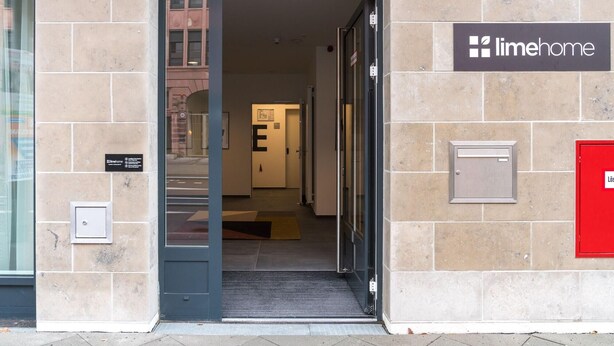 A building entrance with a sign for Limehome, a door labeled 'E', and a red mailbox on the right.