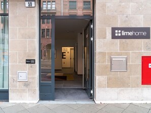 A building entrance with a sign for Limehome, a door labeled 'E', and a red mailbox on the right. - Limehome Frankfurt Gutleutstraãÿe (Frankfurt)