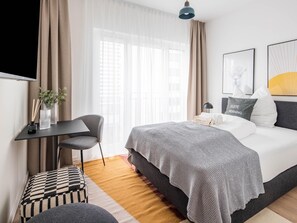 A modern hotel room with a bed, a desk, a chair, and a window with curtains. - Limehome Frankfurt Gutleutstraãÿe (Frankfurt)