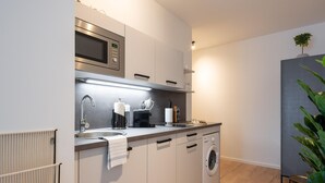 A modern kitchen with a built-in microwave, a sink, a coffee maker, and a washing machine. - Limehome Frankfurt Gutleutstraãÿe (Frankfurt)