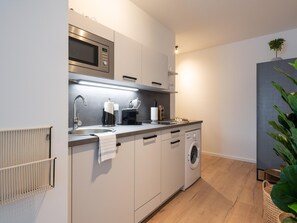 A modern kitchen with a built-in microwave, a sink, a coffee maker, and a washing machine. - Limehome Frankfurt Gutleutstraãÿe (Frankfurt)