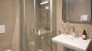 A modern bathroom with a glass-enclosed shower, a white sink, and a mirror above the sink. - Limehome Frankfurt Gutleutstraãÿe (Frankfurt)