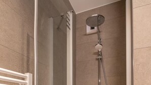 A glass-enclosed shower with a handheld showerhead, a wall-mounted faucet, and a white towel rack. - Limehome Frankfurt Gutleutstraãÿe (Frankfurt)