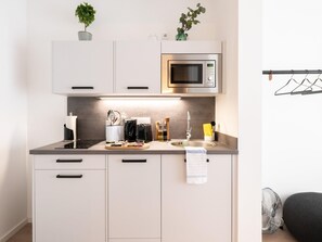 A modern kitchen with a microwave, stove, sink, and cabinets. - Limehome Frankfurt Gutleutstraãÿe (Frankfurt)