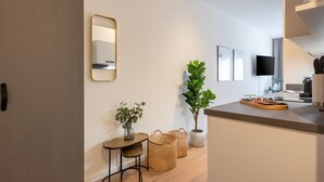 A modern kitchen with a built-in oven, a dining table with a tray, and a large potted plant.
