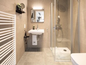 A modern bathroom with a glass shower enclosure, a white sink, and a towel rack. - Limehome Frankfurt Gutleutstraãÿe (Frankfurt)