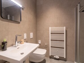 A bathroom with a white sink, mirror, and toilet. - Limehome Frankfurt Gutleutstraãÿe (Frankfurt)
