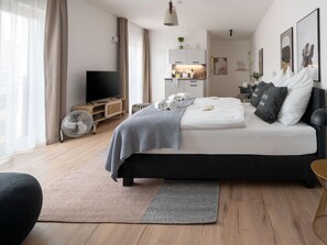 A modern bedroom with a bed, a TV, a kitchenette, and a large window. - Limehome Frankfurt Gutleutstraãÿe (Frankfurt)