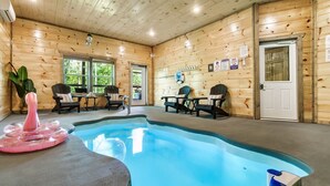 An indoor pool area with wooden walls, a pool, lounge chairs, and a door. - Private Indoor Pool/Pet Stays Free/HotTub/Movie (Sevierville)