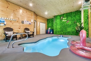 Uma área de piscina com paredes de madeira, uma parede verde com texto e duas cadeiras.
