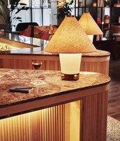 Eine Bar mit Holzlampen, einem Glas Rotwein und einem Notizbuch auf einer Marmorplatte.
