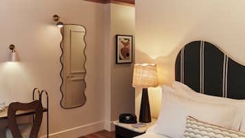 Una habitación de hotel con una cama, una silla, una mesita de noche con lámpara, un cuadro enmarcado en la pared y una puerta de diseño único.