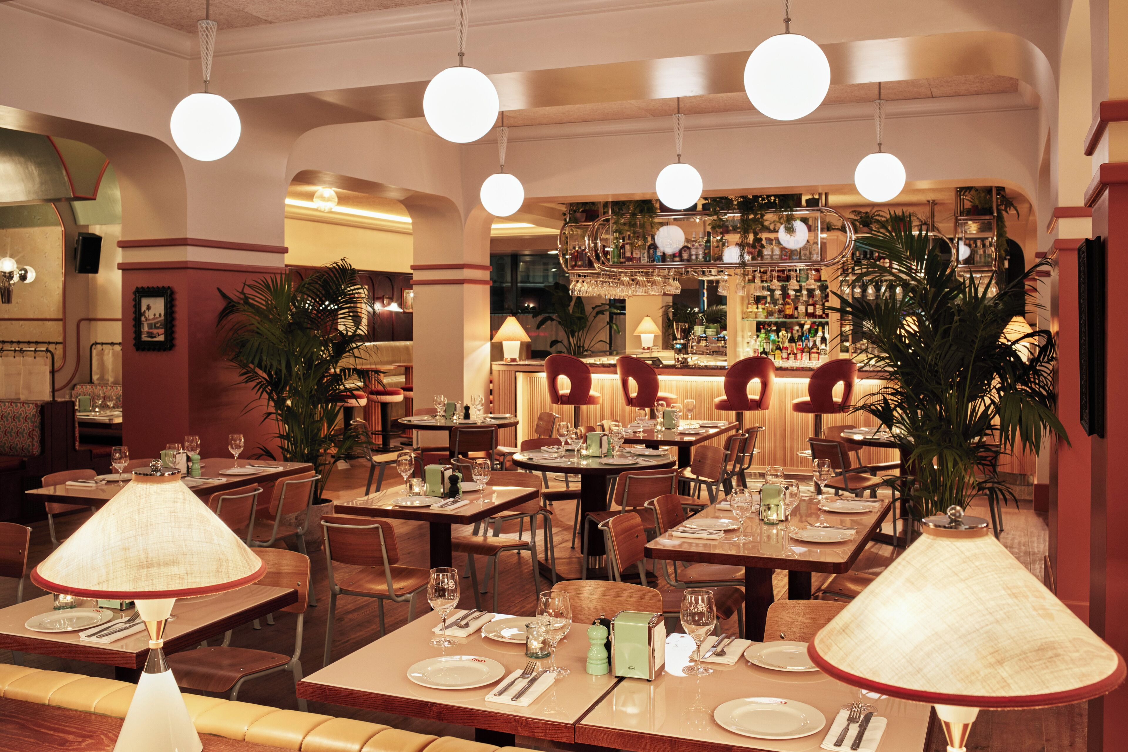 Een restaurant met verschillende eettafels, stoelen en hanglampen.