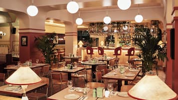 A restaurant with multiple dining tables, chairs, and hanging lamps.