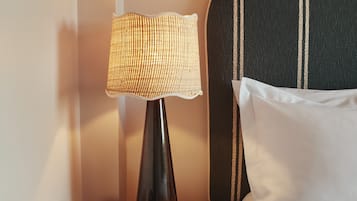 A hotel room with a bedside lamp, a remote control, and a book titled "Art London" on a small table.