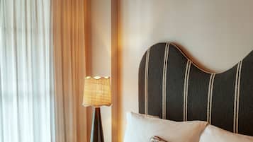 Ein Hotelzimmer mit einem Bett, einem Nachttisch, einer Lampe und einem Vorhangfenster.