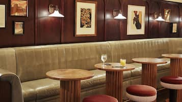 Un interior de restaurante con asientos tipo cabina de cuero, mesas de madera y taburetes acolchados rojos.