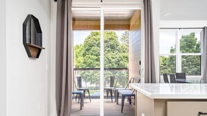 Una cocina moderna con un ventanal grande, un área de comedor con sillas y una puerta corrediza de vidrio que da a una terraza exterior.