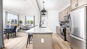Una cocina moderna con una isla central, electrodomésticos de acero inoxidable y un comedor con vistas.