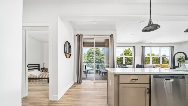 Una cocina moderna con una isla central, lavavajillas integrado y ventanas amplias.