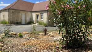 Une maison avec un toit en pente et un jardin agrémenté de plantes et de fleurs.