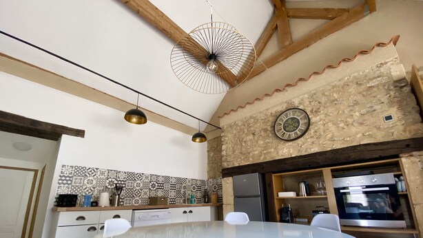 Une cuisine avec une table ronde, des chaises, un réfrigérateur, un four et un ventilateur de plafond décoratif.