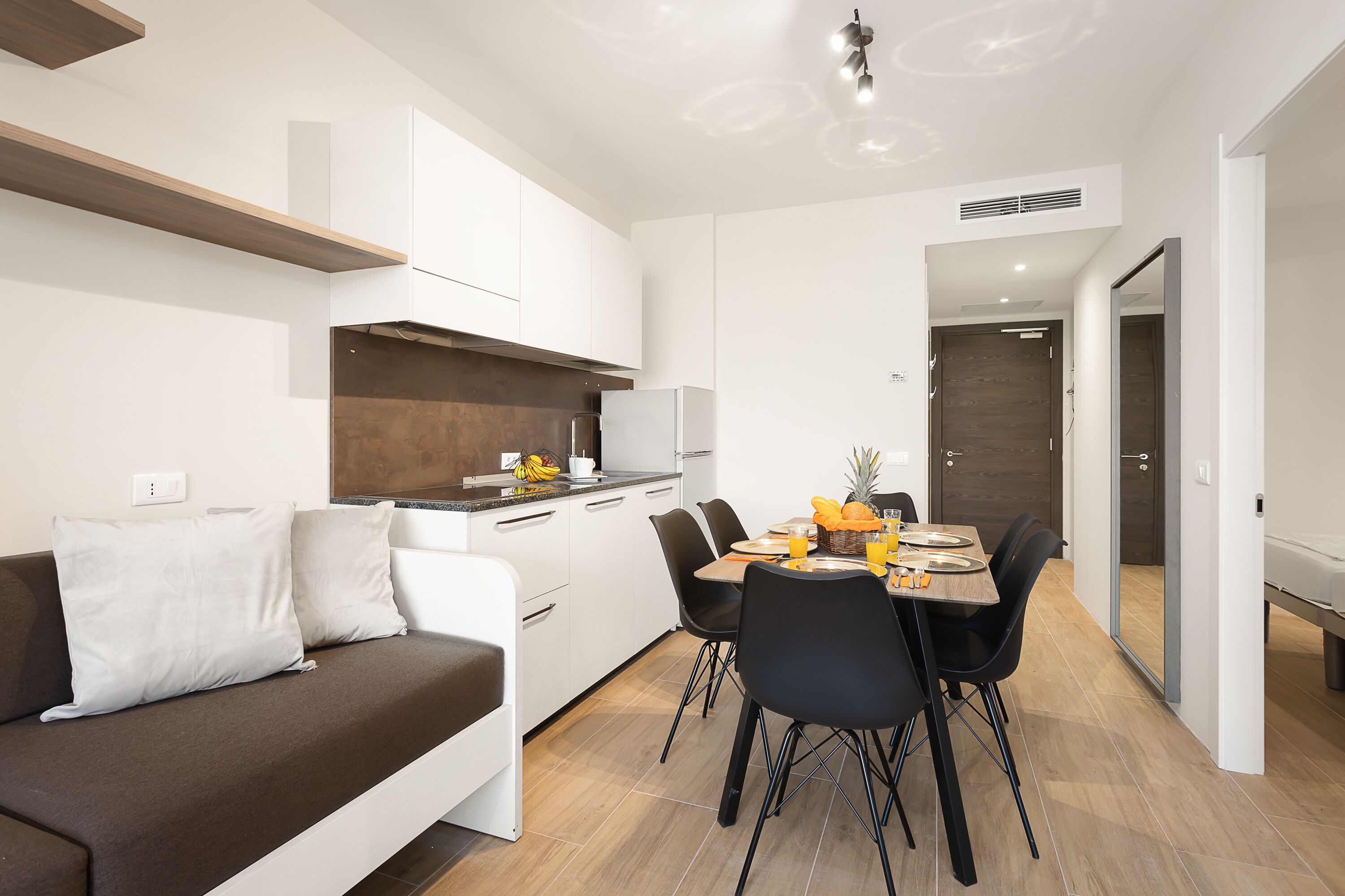 A modern kitchen with white cabinets, a wooden countertop, and a dining area with a table and chairs.