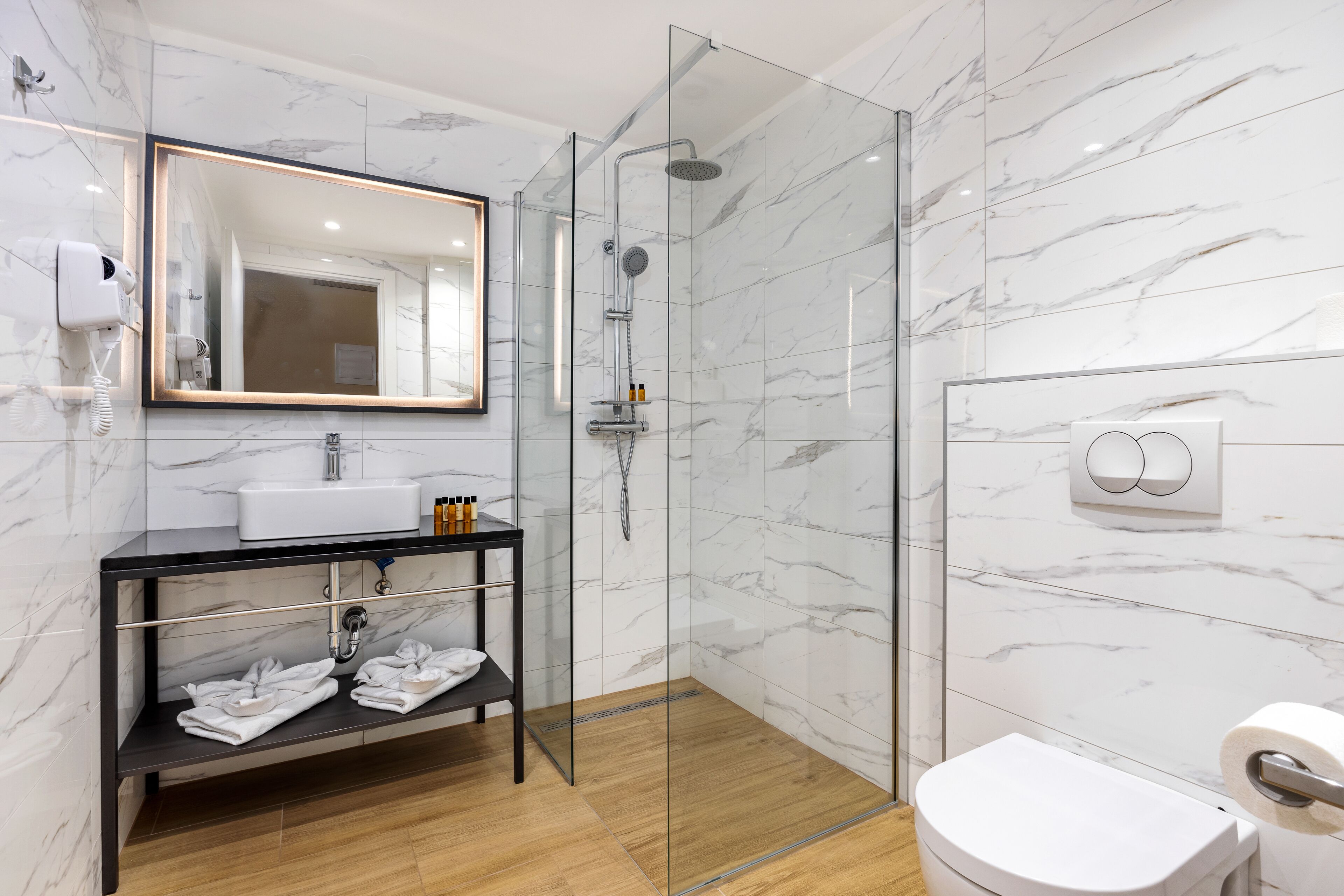 A modern bathroom with a glass-enclosed shower, a white sink, and a toilet.