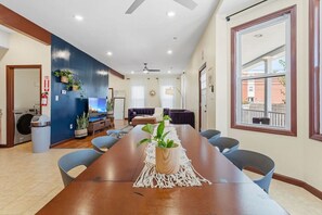Ein geräumiger Konferenzraum mit einem langen Tisch, Stühlen und einem Deckenventilator.
