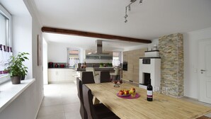 A modern kitchen with a wooden dining table, chairs, and a wine bottle.