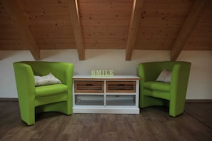 Une pièce avec deux fauteuils verts, une console blanche sur laquelle est inscrit le mot «
Sourire
», et un plafond en bois.