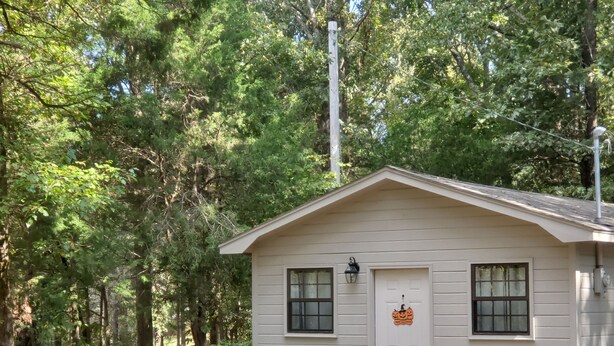 A small, single-story cabin with a front door, two windows, and a bench outside. - Quiet, country space close to Oxford (Oxford)