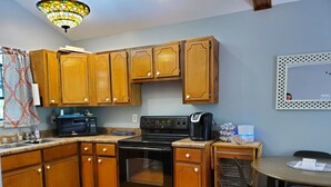 A kitchen with wooden cabinets, a stove, a microwave, and a coffee maker. - Quiet, country space close to Oxford (Oxford)