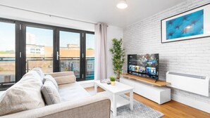Ett modernt vardagsrum med en soffa, ett soffbord, en tv och en växt.