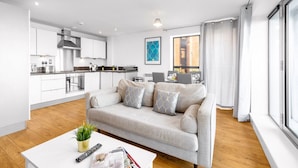 En modern lägenhet med ett kök, ett vardagsrum med soffa och stora fönster.