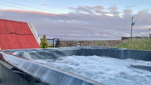 Un jacuzzi con una pared de piedra y un techo rojo al fondo.