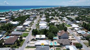 Vista aerea di una zona residenziale con case, una piscina e vista sull'oceano.