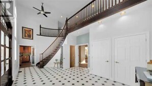 A spacious hallway with a black and white checkered floor, a wooden staircase, and white doors. - Luxury Villa next to golf course (LaSalle)
