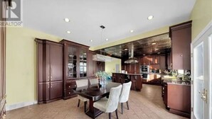 A spacious kitchen with dark wooden cabinets, a central island, and a dining area with two chairs. - Luxury Villa next to golf course (LaSalle)