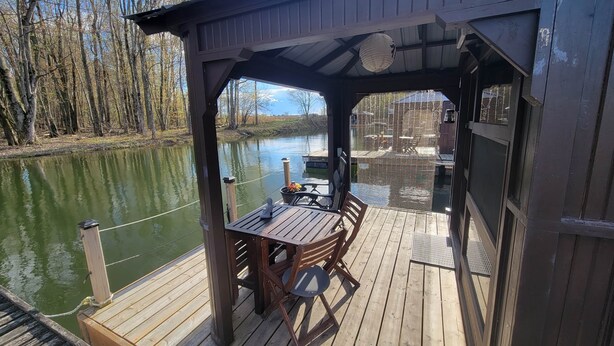 A wooden deck with a table and chairs, overlooking a body of water.