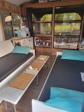 A cabin with two beds, a small kitchenette, and a view of the outdoors.