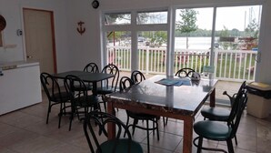 Un espace repas comprenant une table et des chaises, avec vue sur l’extérieur et une porte.