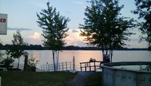 A lakeside view with a dock, trees, and a sign. - Aloberge 4 (Lacolle)