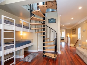 Habitación de varios niveles con una escalera de caracol, literas y un pasillo que conduce a otra habitación.