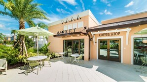 An outdoor patio area with tables and chairs, a coffee shop, and a market. - Beautiful home across from the Clubhouse! 5 Star Reviews! Fun Resort!  (Kissimmee)