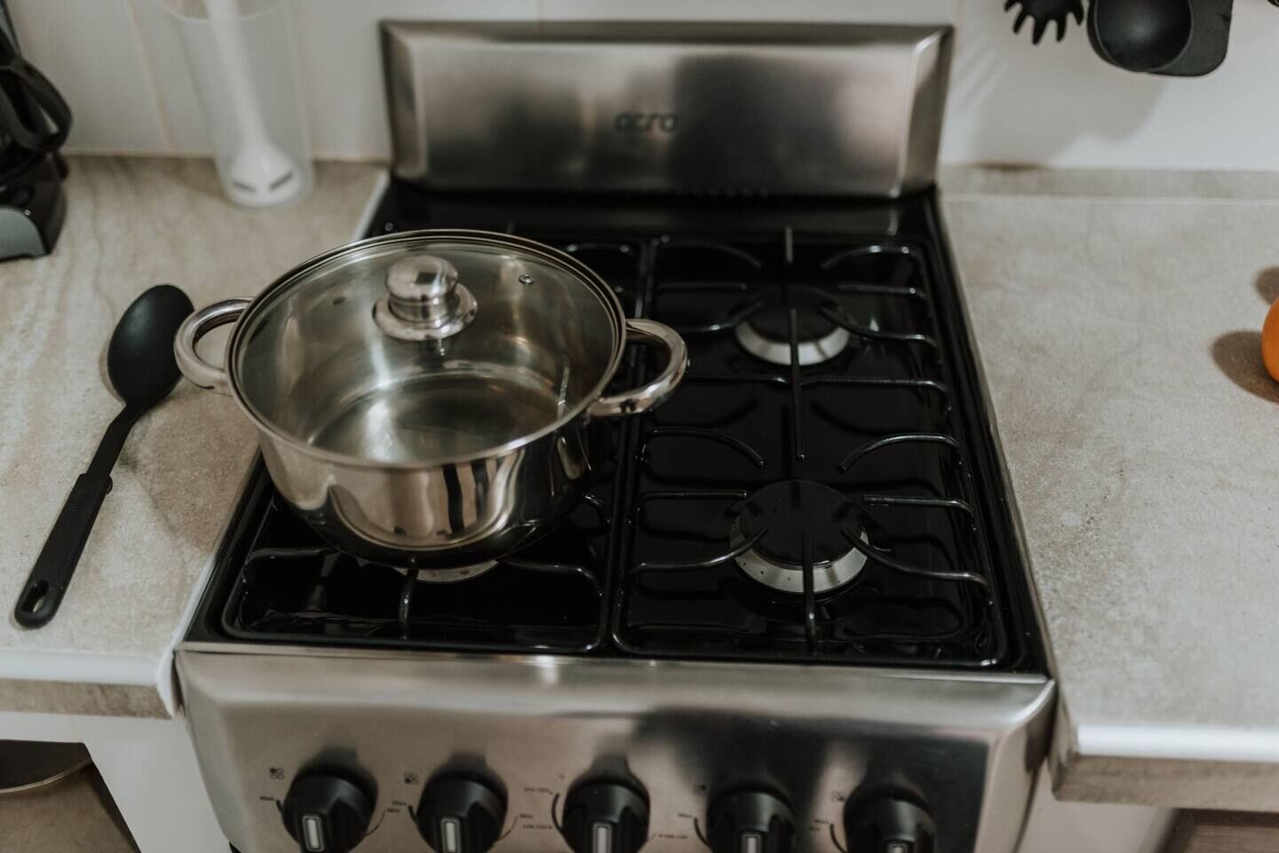 A stainless steel stove with four burners and a pot on top.