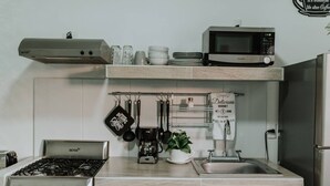 Eine kleine Küche mit Gaskochfeld, Mikrowelle und Kaffeemaschine.