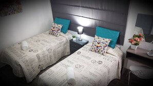 Une chambre d’hôtel avec deux lits, chacun recouvert d’une couvre-lit à motifs, une table de chevet avec une lampe et un bureau avec une chaise.